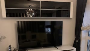 A living room with a flat-screen TV on a white entertainment unit, a sofa, and two patterned cushions. - Vacation home with barbecue, great access to Porto (Alfena)
