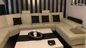 A modern living room with a sectional sofa, a coffee table with decorative items, and a striped wall. - Vacation home with barbecue, great access to Porto (Alfena)