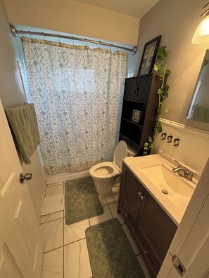 Ein Badezimmer mit Toilette, Waschbecken, Duschvorhang und einer Pflanze.