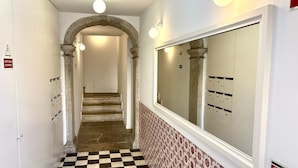 A hallway with a checkered floor, a large mirror, and a staircase leading to another area. - Alfama Premium (Lisbon)