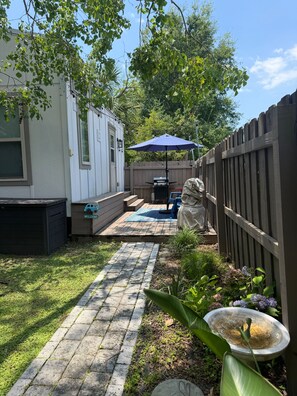 A backyard with a patio, a barbecue grill, a welcome sign, and a wooden fence.