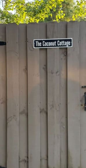 Una cerca de madera con un letrero que dice 'The Coconut Cottage'.