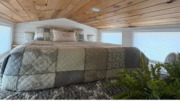 A bedroom with a wooden ceiling, a large bed with a quilt, and a window with blinds. - Private Tiny Home w/ Courtyard, Grill & Quiet Location – Sleeps 2 (Pensacola)