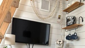 A kitchen with a TV, coffee maker, and wooden shelves. - Private Tiny Home w/ Courtyard, Grill & Quiet Location – Sleeps 2 (Pensacola)