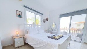 Un dormitorio con cama, mesita de noche, cómoda y vistas al exterior.