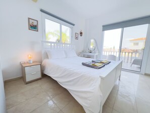 Ein Schlafzimmer mit Bett, Nachttisch, Schminktisch und Blick nach draußen.