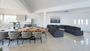 Un espacio habitable moderno con comedor, cocina y un amplio sofá seccional gris.
