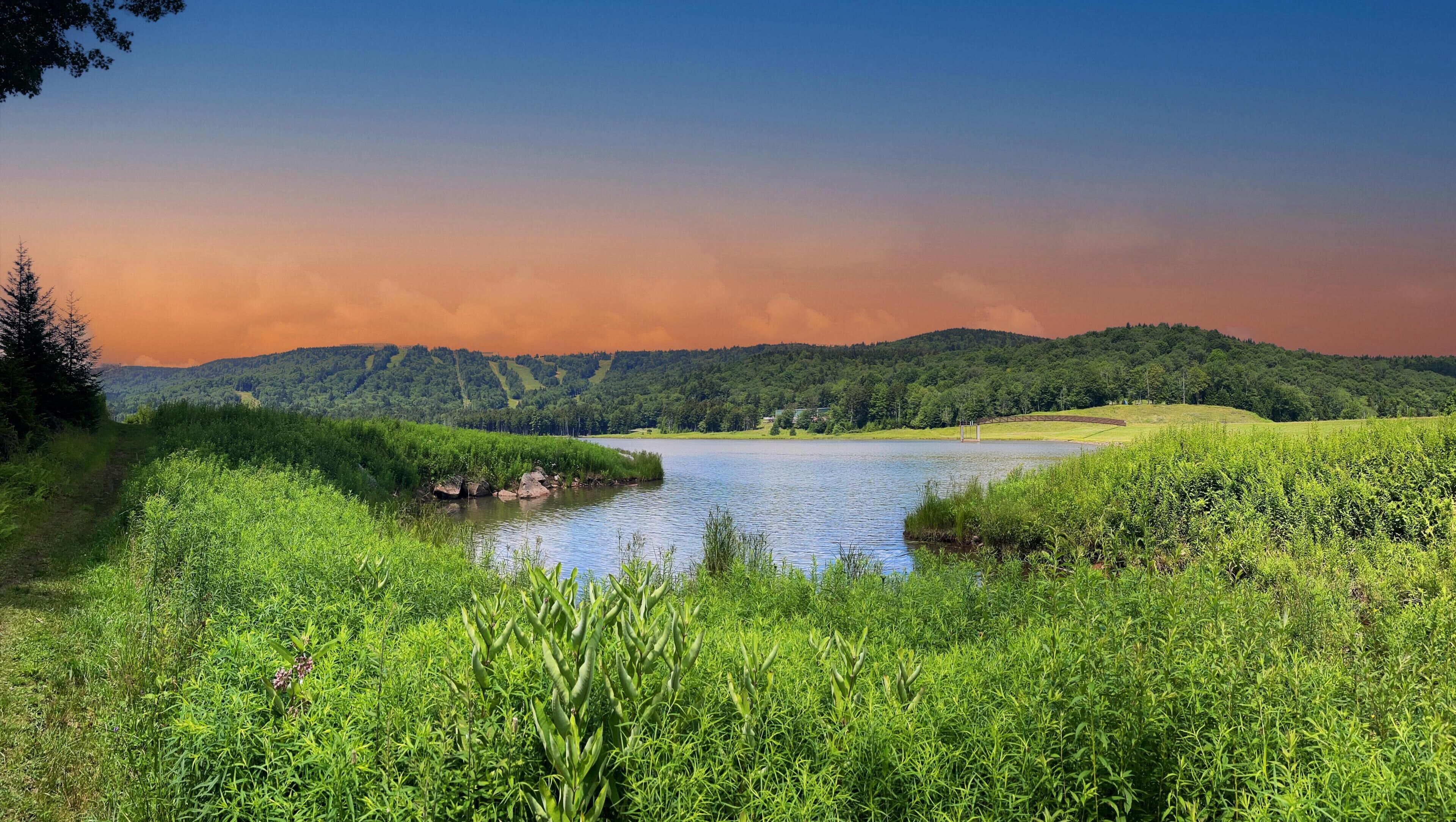 Une rivière bordée d’une végétation luxuriante et entourée de collines.