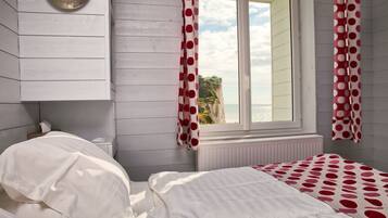 Un dormitorio con cama, radiador y ventana con cortinas.