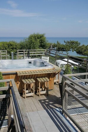 A wooden deck with a hot tub, outdoor seating, and a view of the sea. - Hotel The Originals Le Cise (Ault)