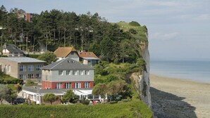 Una propiedad costera con vista al acantilado, casas con diversos estilos de techo y una playa al fondo.