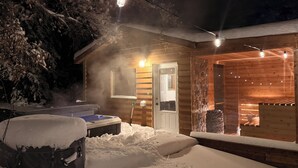 Una baita di legno con idromassaggio, un muro in pietra e luci a stringa.