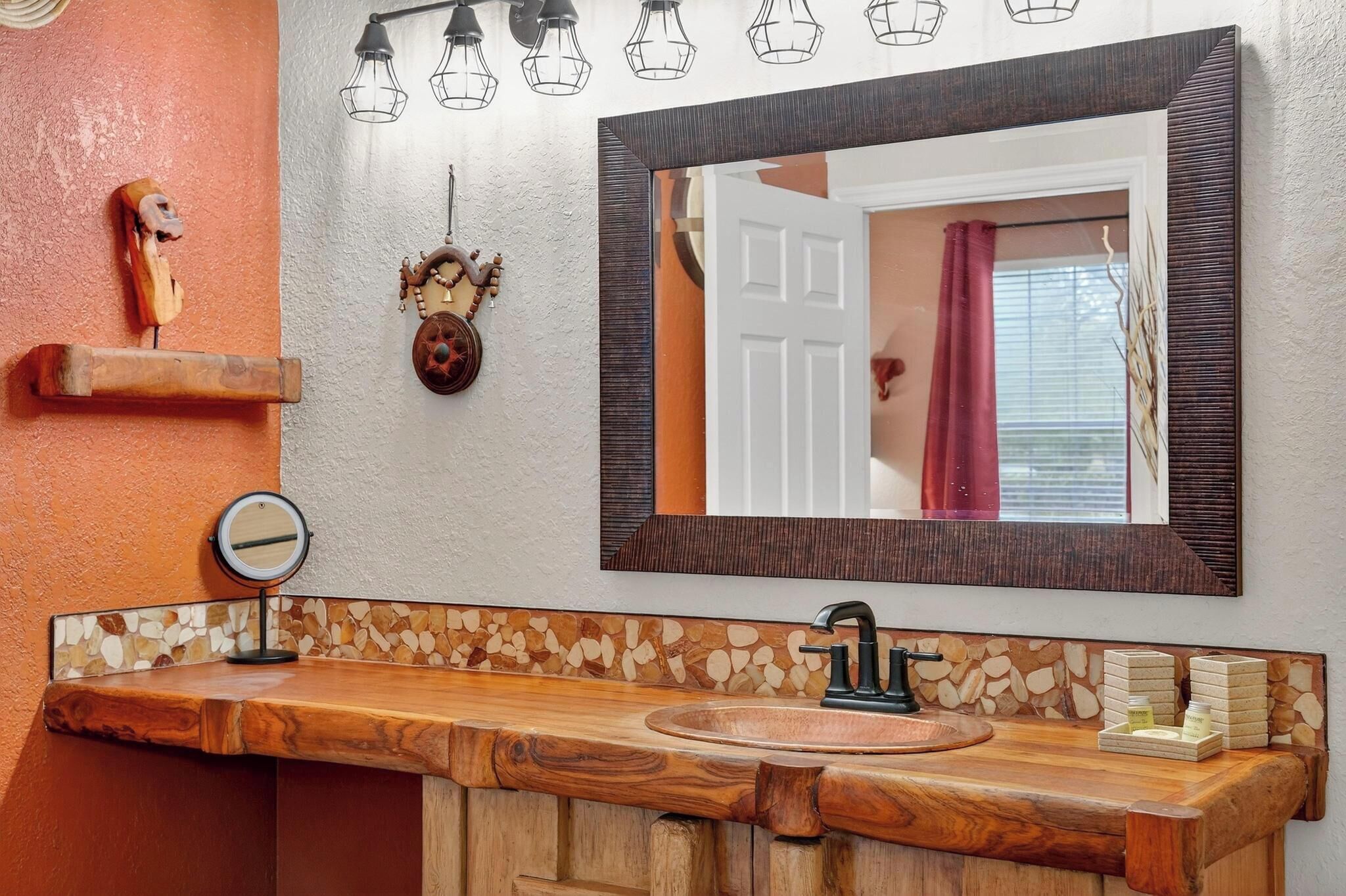 A bathroom with a wooden vanity, a large mirror, and decorative wall art.