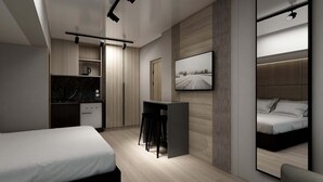 Une chambre d’hôtel moderne équipée d’un lit, d’un bureau, d’une petite kitchenette et d’un grand miroir.