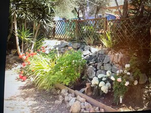 A garden with a stone wall, various plants, and a wooden fence. - Air-conditioned villa with pool and jacuzzi, toulon ouest (Toulon)
