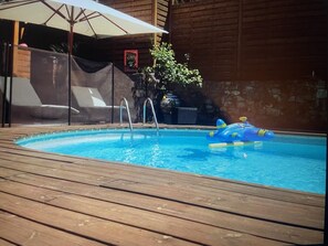 A wooden deck with a swimming pool, a lounge chair, and a covered area with an umbrella. - Air-conditioned villa with pool and jacuzzi, toulon ouest (Toulon)