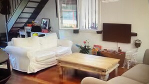 A living room with a white sofa, a wooden coffee table, and a TV mounted on the wall. - Air-conditioned villa with pool and jacuzzi, toulon ouest (Toulon)