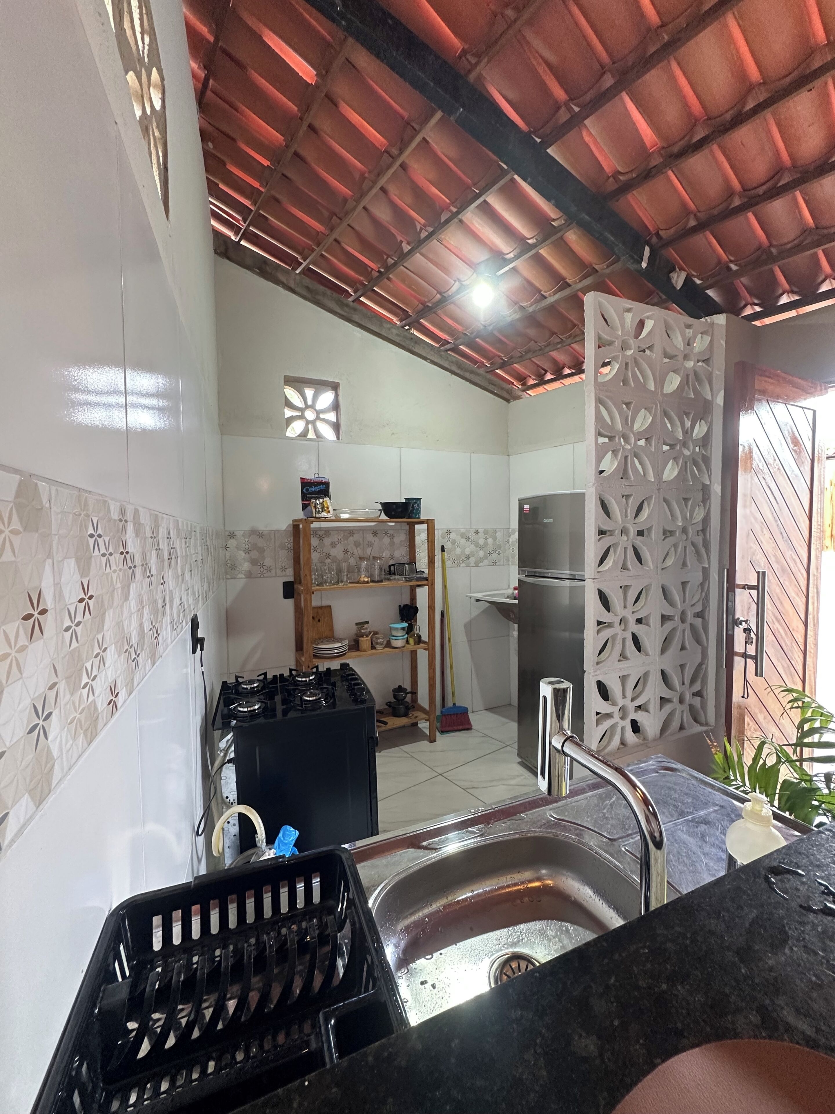 Cozinha com fogão a gás, pia e divisória decorativa.