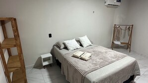 Un dormitorio con cama, escalera de madera, mesita de noche blanca y perchero.