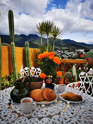 A table with a cactus, marigold flowers, a ceramic pot, and a small figurine. - Casa Donaji Guest House (Oaxaca)
