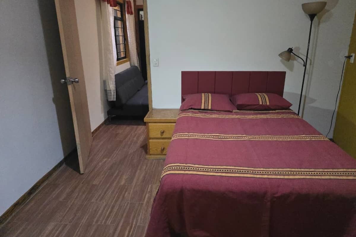 A bedroom with a bed, bedside table, and a lamp.