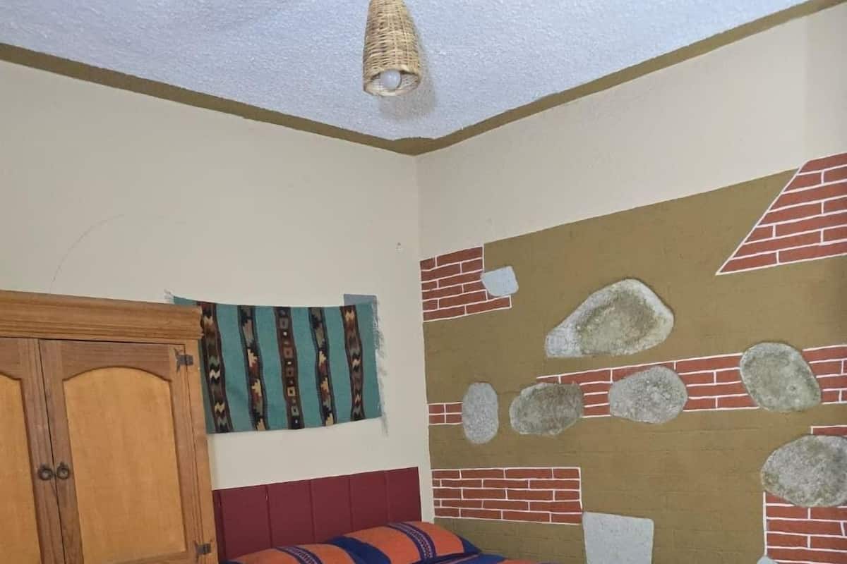 A bedroom with a bed, wooden wardrobe, and a wall mural.