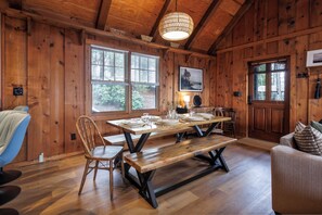 A wooden interior with a dining table, chairs, a bench, a sofa, and a large window. - Views • Hot Tub • Fenced Yard • Near Downtown (Blue Ridge)