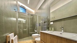 Un baño moderno con ducha envuelta en vidrio, inodoro y tocador de madera con lavamanos.