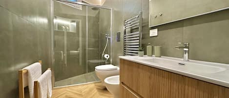A modern bathroom with a glass-enclosed shower, a toilet, and a wooden vanity with a sink.