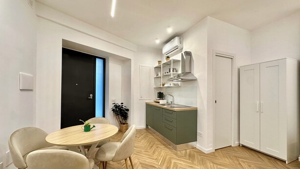 Una cocina moderna con comedor, que incluye una mesa redonda, sillas, estufa integrada y armarios.