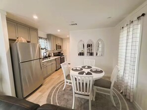 A compact kitchen with a refrigerator, microwave, and stove. There is a dining table with chairs and a rug. - Hudson Horse Ranch (Hudson)