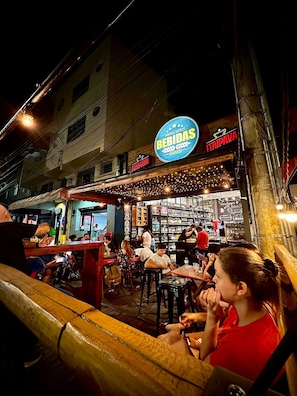 A bar with a neon sign, outdoor seating, and a view of the street. - VA Apart Hotel Savassi (Divinópolis)