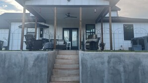 A covered porch with a ceiling fan, a staircase leading to the entrance, and a fenced outdoor area with chairs and tables. - Spacious 4-bedroom, 3-bath, 2-story house in the town of Wellston, Oklahoma (Wellston)
