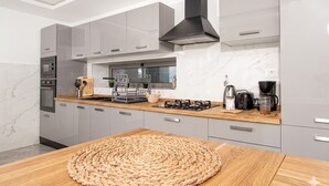 Une cuisine moderne avec des meubles gris, une hotte noire, un plan de travail en bois et un set de table en fibres tressées.