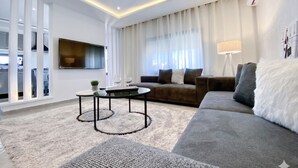 Un salon moderne avec un canapé, une table basse, un téléviseur et une fenêtre avec des rideaux.