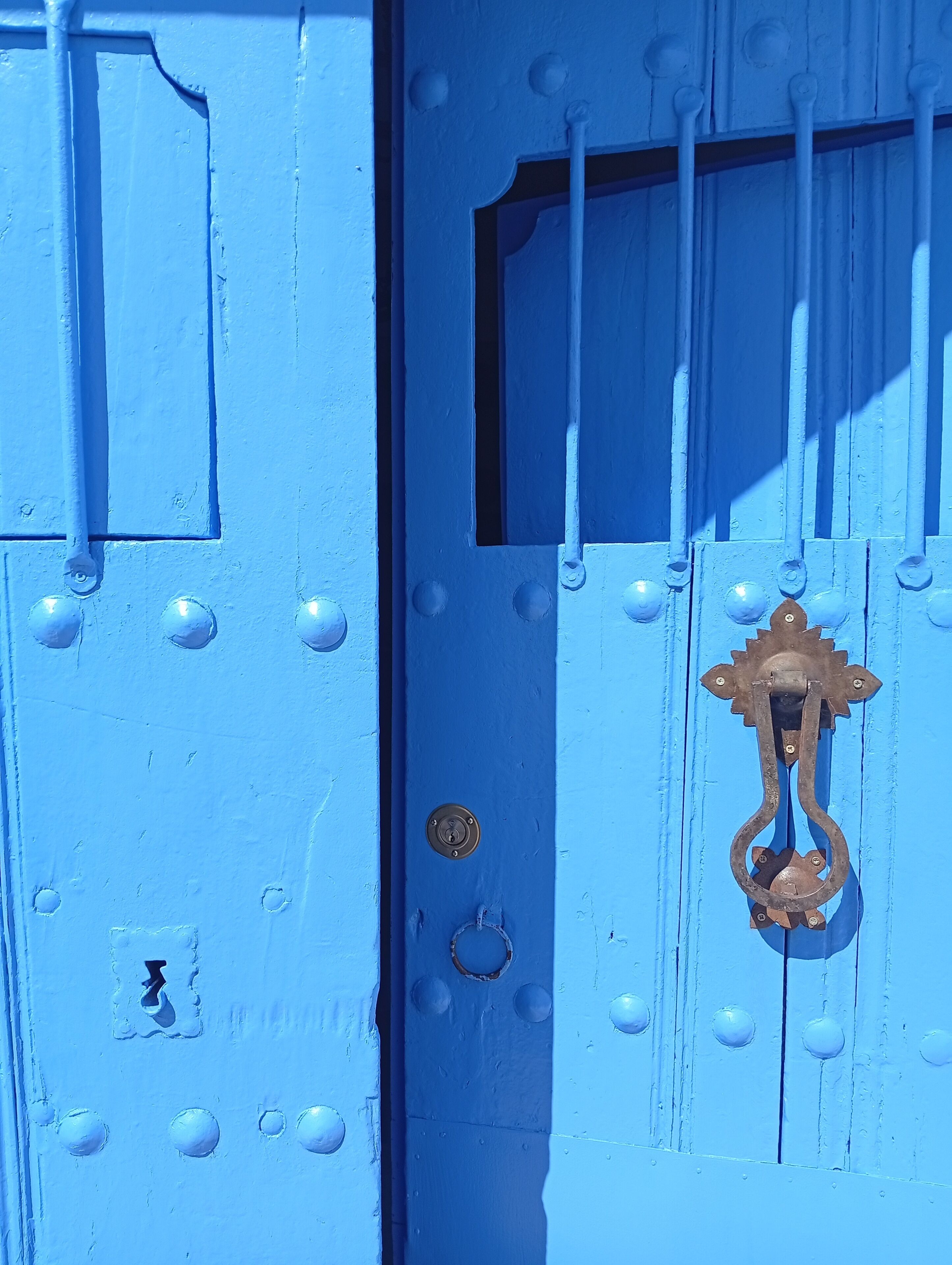 Una porta blu con una maniglia metallica e una finestra sopra.