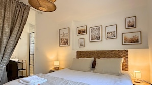 A hotel room with a large bed, two bedside tables, a wicker headboard, and wall-mounted artwork. - Horizon air-conditioned villa with private heated pool (SAINT RAPHAEL)
