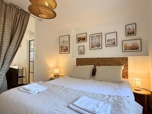 A hotel room with a large bed, two bedside tables, a wicker headboard, and wall-mounted artwork. - Horizon air-conditioned villa with private heated pool (SAINT RAPHAEL)