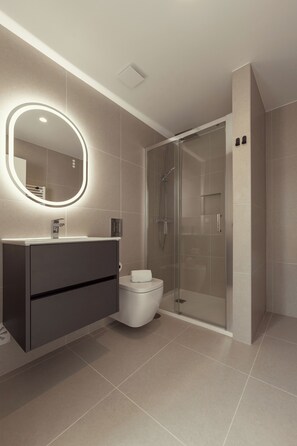 Ein modernes Badezimmer mit Duschkabine aus Glas, einem Waschtisch mit Spiegel und einer Toilette.