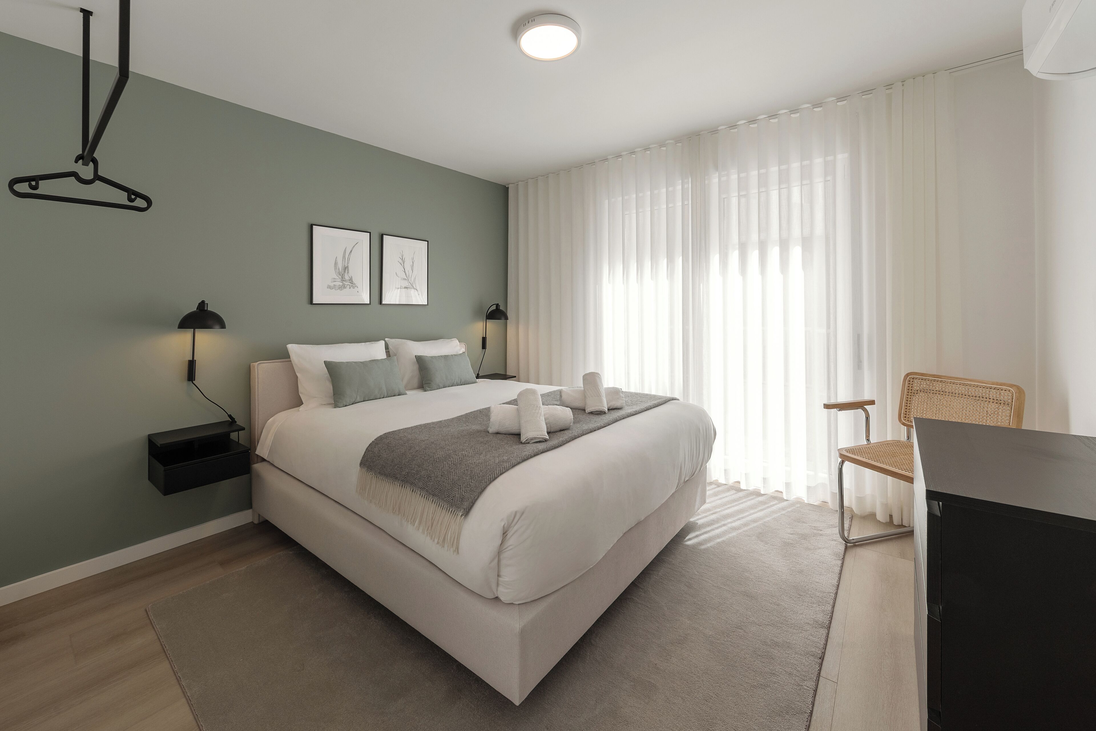 Ein modernes Schlafzimmer mit Bett, Nachttischen, Schreibtisch und Stuhl.