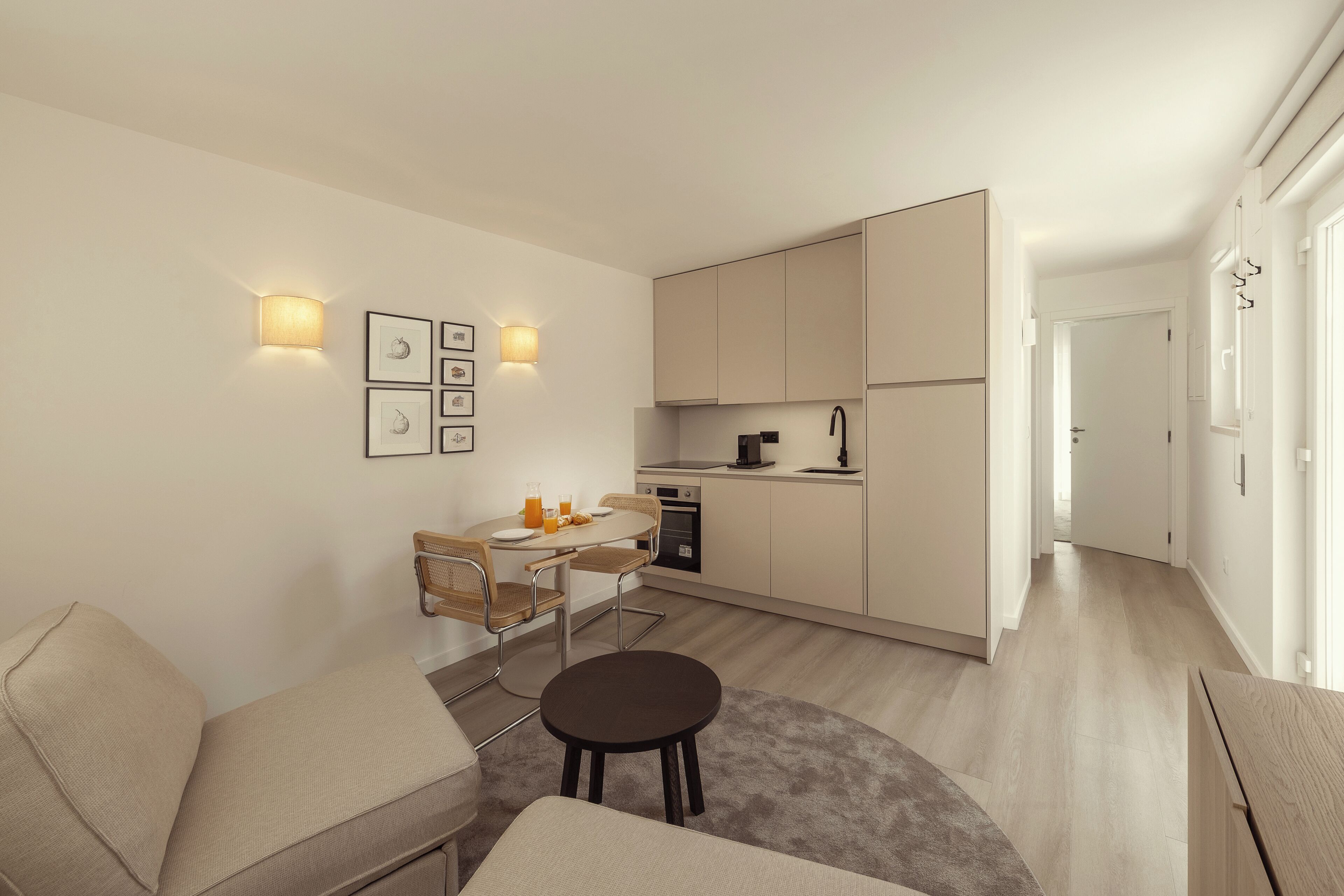 Un appartement moderne comprenant un coin repas, une kitchenette et un espace de vie avec un canapé et une petite table ronde.