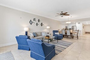 Ein Wohnzimmer mit einer Couch, zwei Sesseln, einem Couchtisch und einem Essbereich mit Tisch und Stühlen.