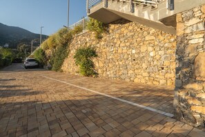 A paved driveway leading to a stone wall with a car parked on the side. - 5 Minutes from the Beaches: Relax by the Pool (Alassio)