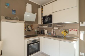 A compact kitchen with a microwave, oven, and sink. - 5 Minutes from the Beaches: Relax by the Pool (Alassio)