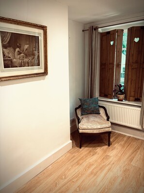 A room with a wooden-framed painting, a chair with a cushion, a window with curtains, and a radiator. - Regency Apartment in tranquil Georgian Setting close to Brighton’s Laines  (Brighton and Hove)