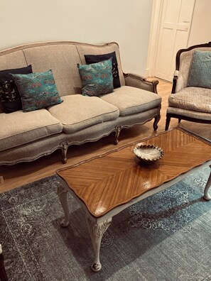 A beige sofa with patterned cushions, a wooden coffee table with a bowl, and a patterned rug. - Regency Apartment in tranquil Georgian Setting close to Brighton’s Laines  (Brighton and Hove)