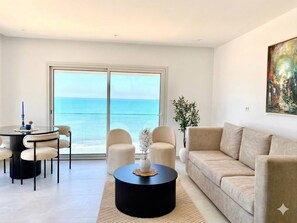 A modern living room with a round coffee table, beige sofas, and a view of the sea through large glass doors. - Luxurious Beachfront Apartment in La Marsa, Tunisia (La Marsa)