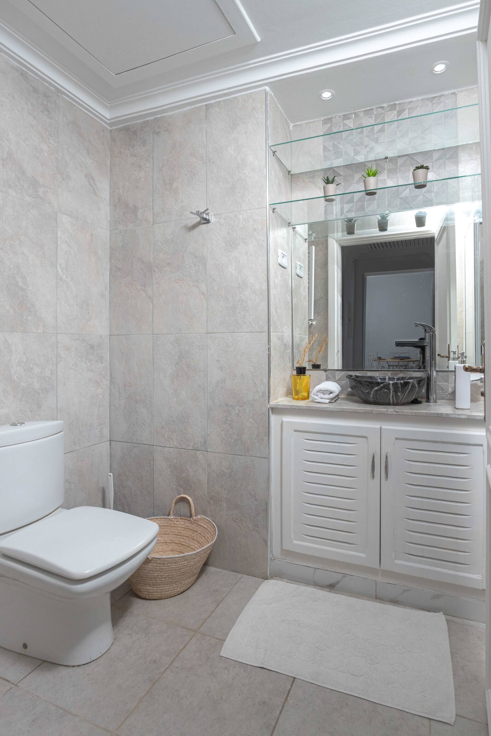 Une salle de bain comprenant des toilettes, un bidet, une douche à parois de verre, un meuble-lavabo avec un miroir et un évier.