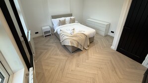 Ein Schlafzimmer mit Bett, Nachttischen, einem Schminktisch und einer Heizung.