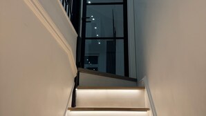 Eine Treppe mit Handlauf, eine Tür mit Glasverkleidung und eine Wandleuchte.